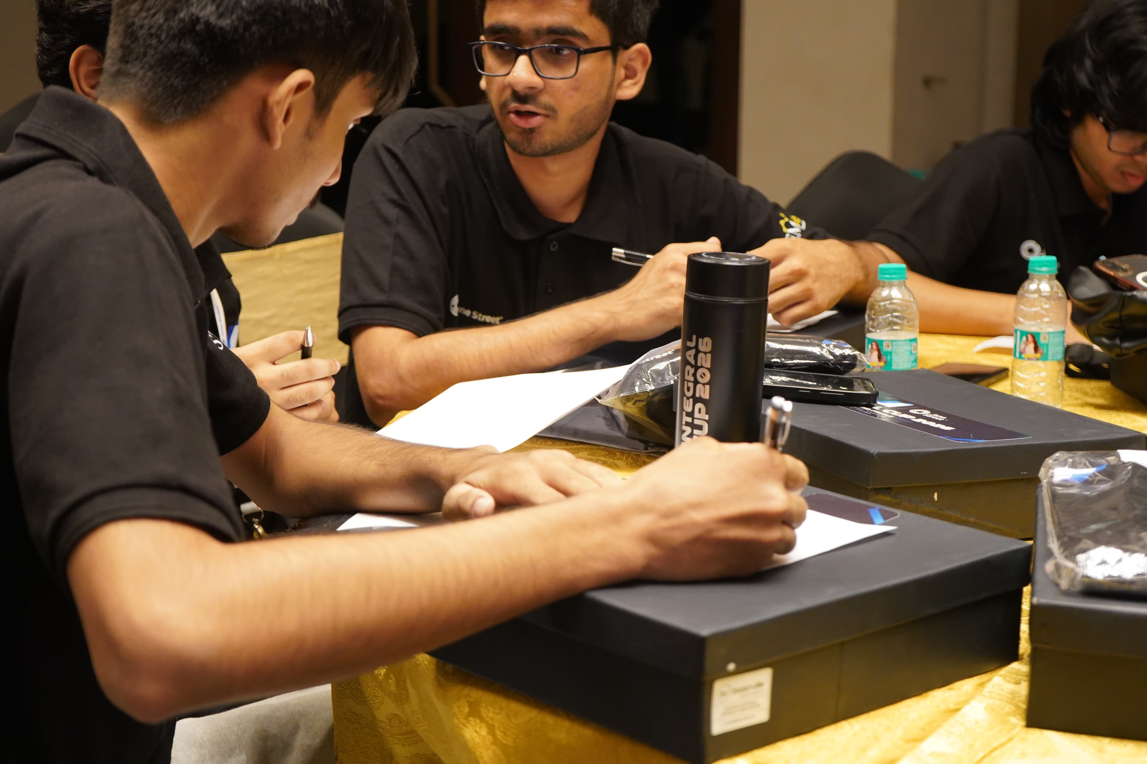 Bhavishy and fellow participants working together around a table during the Estimathon
